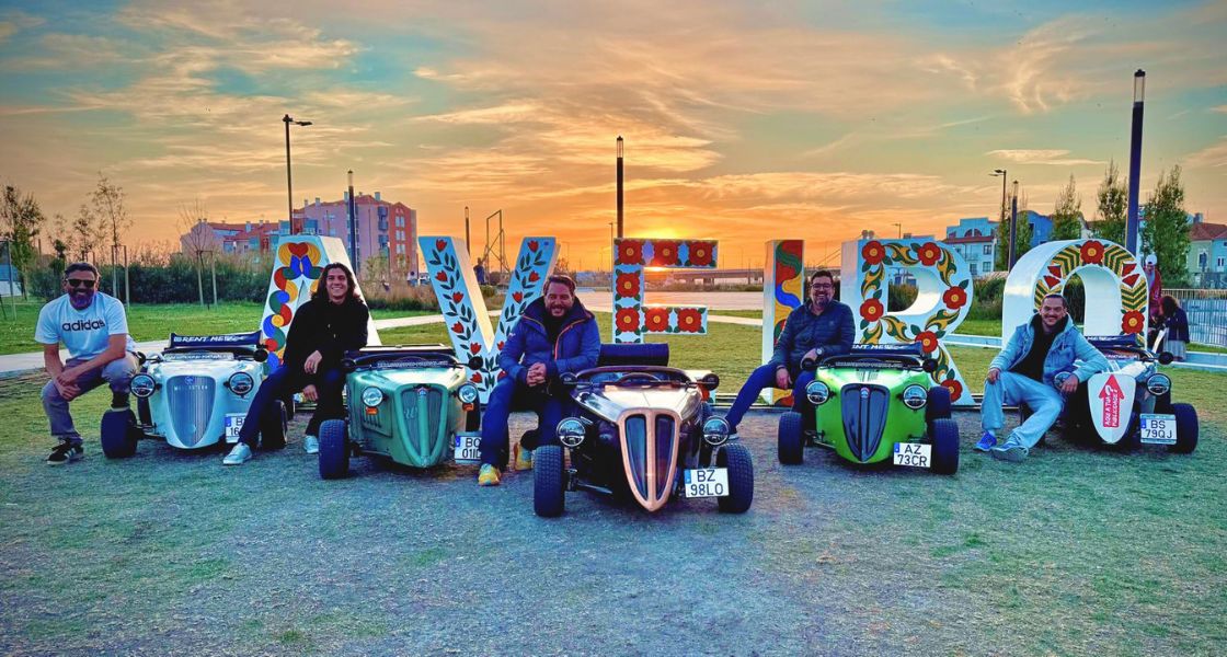 Group of guests with Hot Rod Fun Portugal cars at the colorful Aveiro sign during sunset in Portugal.